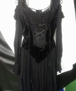 Long black velvet dress with lace-up front and off-the-shoulder sleeves, hanging on a white hanger.